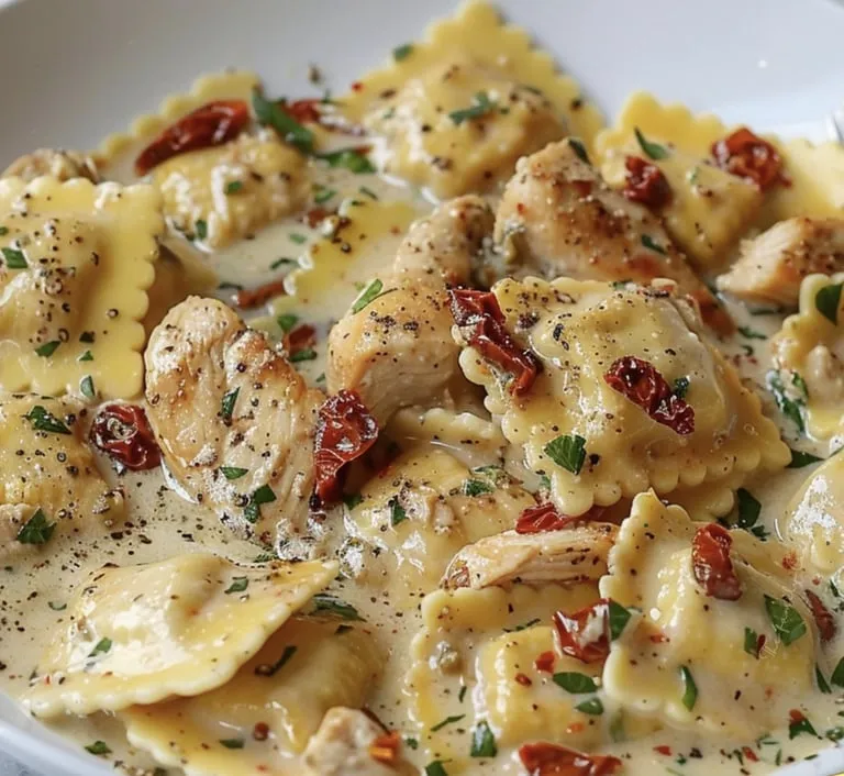 Plate with chicken, sun-dried tomato, ravioli, and red peppers tossed together.