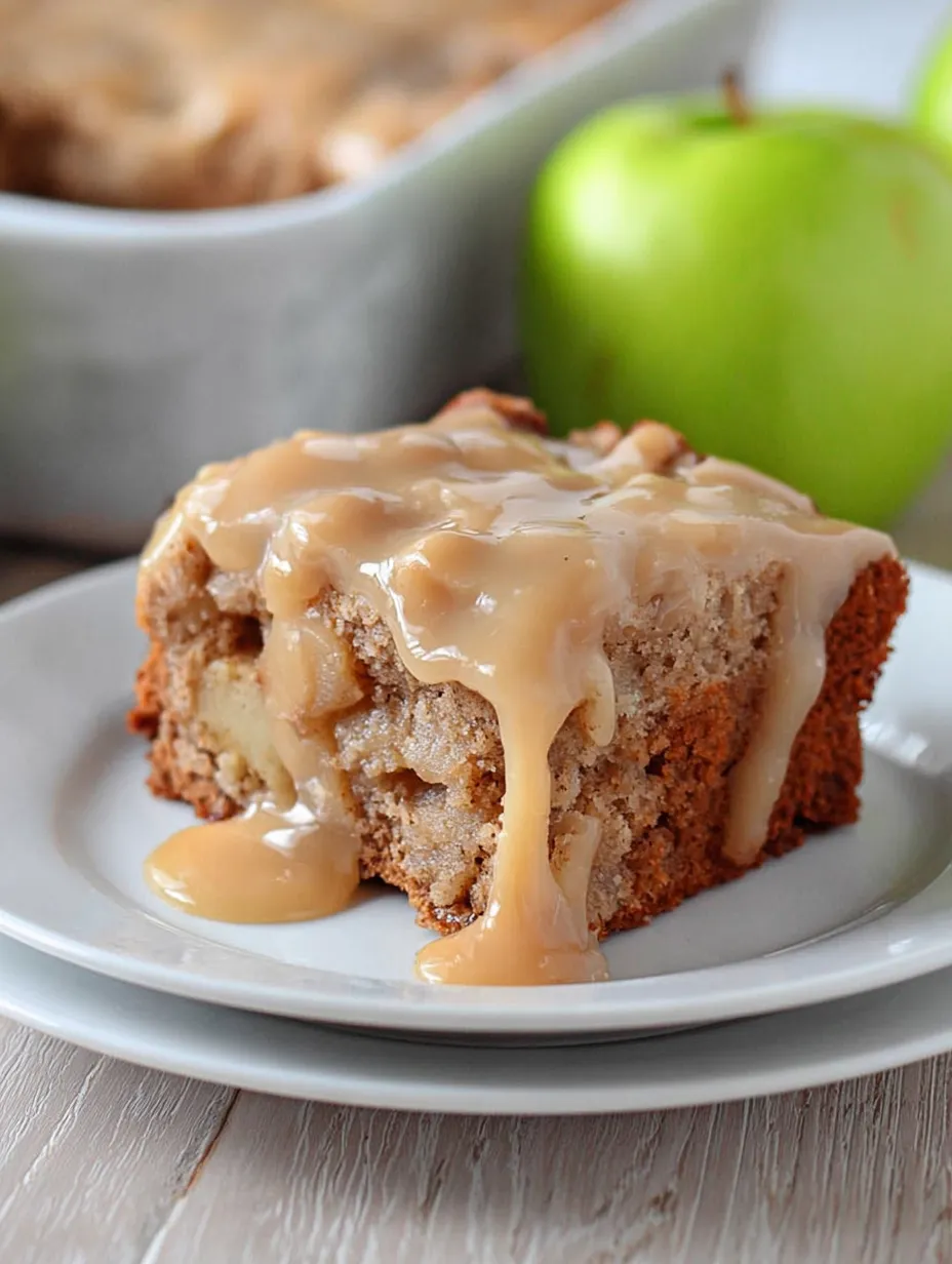 Slice of moist cake on a white plate with gooey caramel sauce.