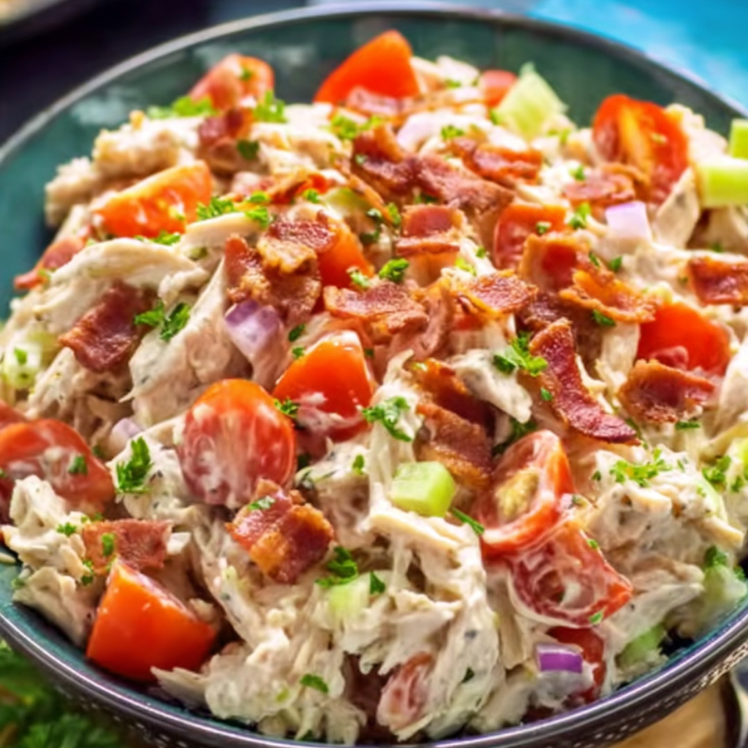 Chicken salad in a bowl next to tomatoes.