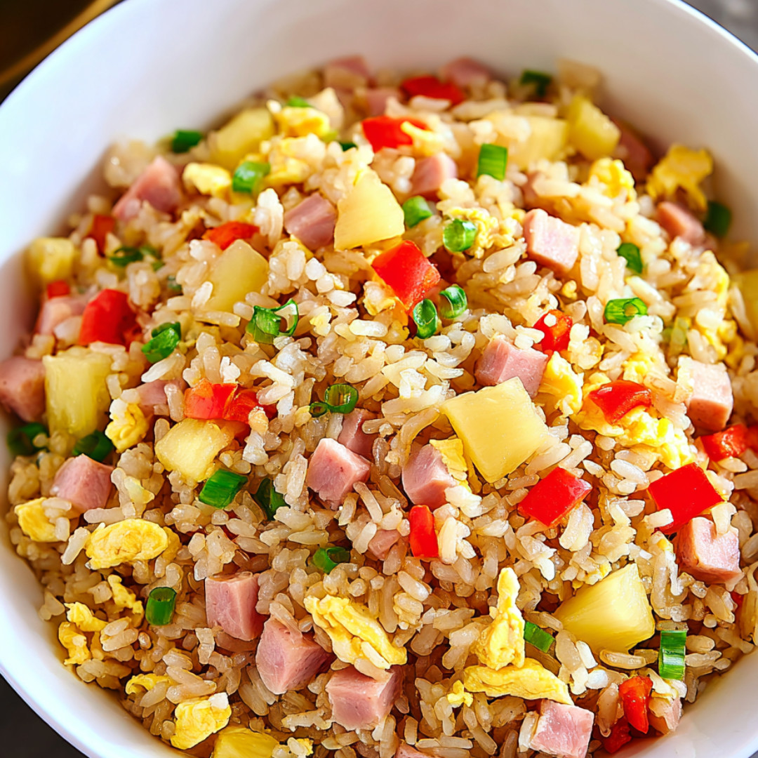 A bowl packed with rice, pineapple, and ham chunks.