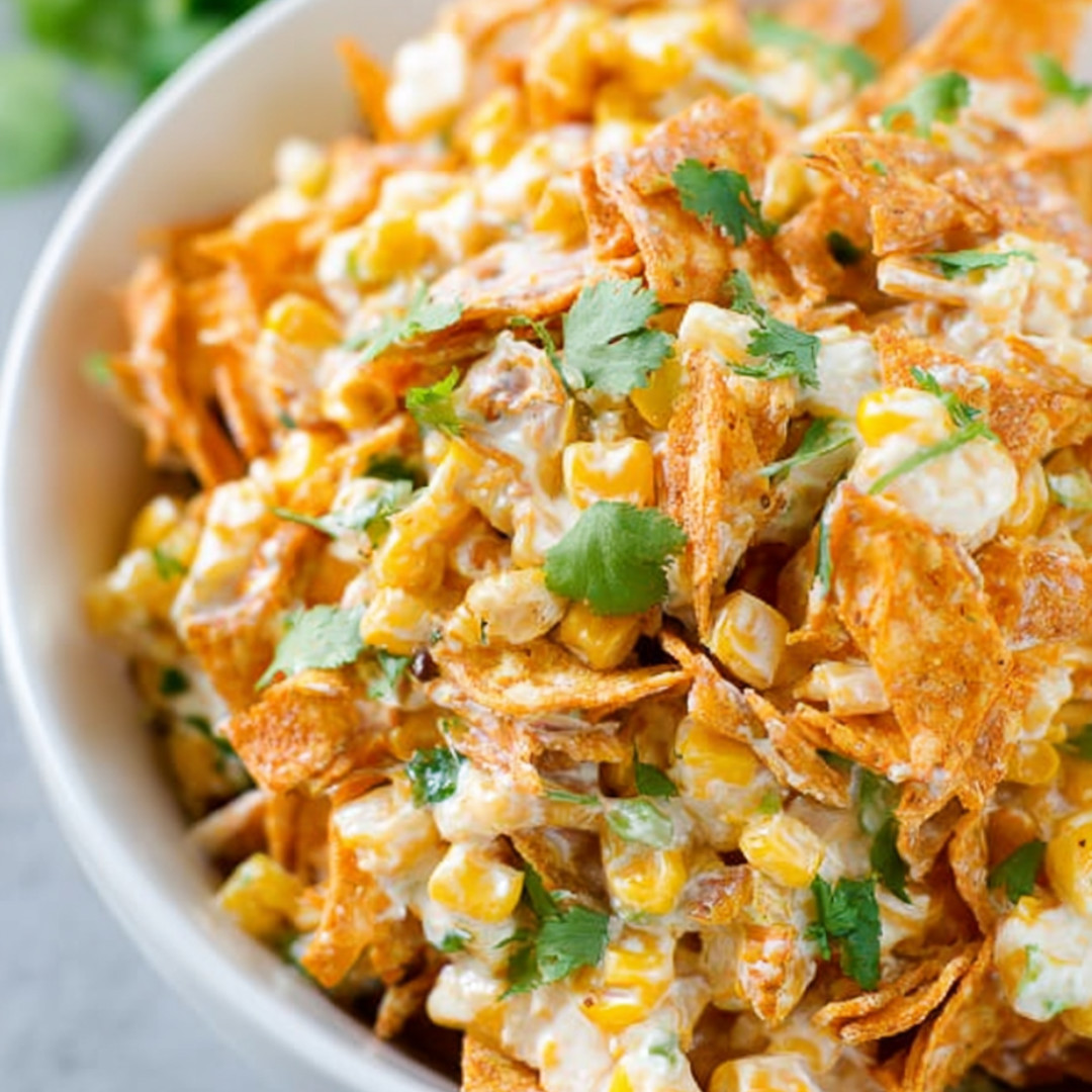 Corn chips in a bowl with green onions on top.