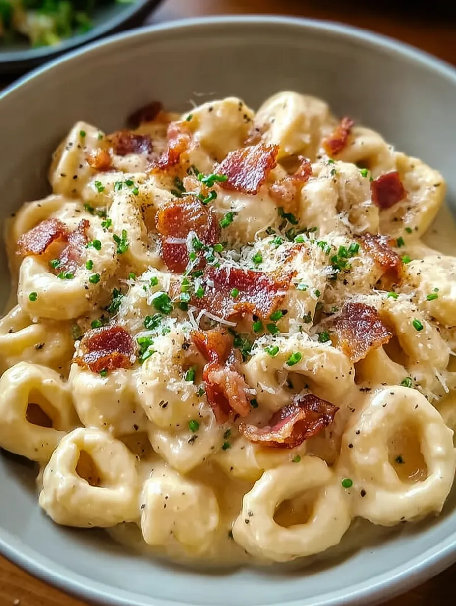 A bowl of pasta with bacon and cheese.