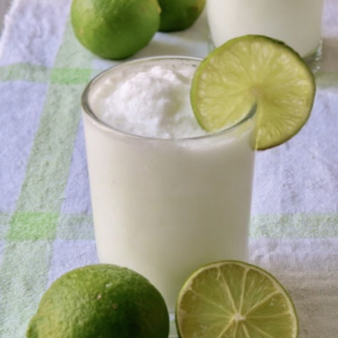 Glass filled with coconut drink and limes on top.