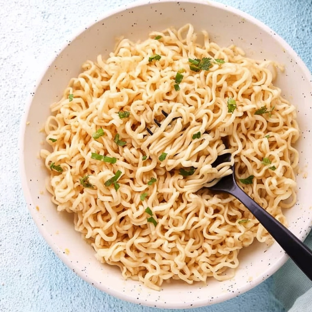 A bowl with noodles and bright green onions.
