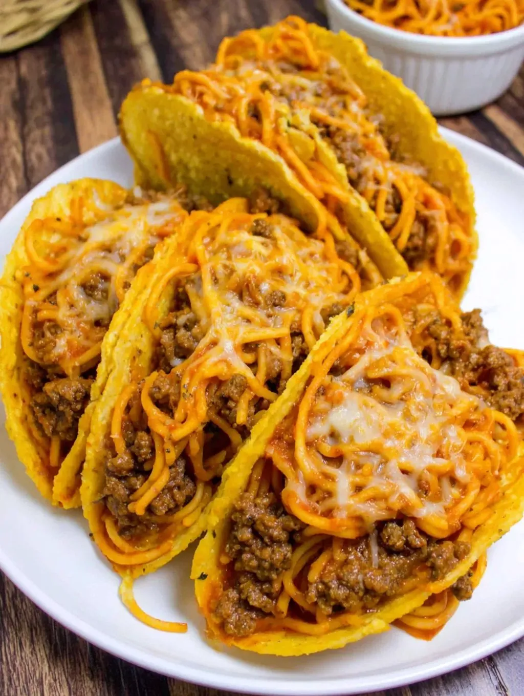 A plate full of tacos packed with cheese and meat.