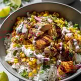 Loaded bowl with rice, chicken, corn, and sliced onions.