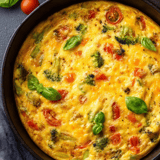 Vegetable omelet close-up showing tomatoes and broccoli.
