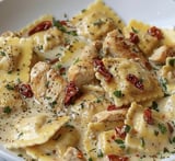 Plate with chicken, sun-dried tomato, ravioli, and red peppers tossed together.