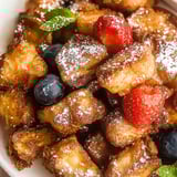 Bowl loaded with golden toast bites topped with fresh fruit.