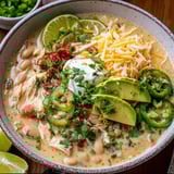 Hot bowl filled with chicken chunks, beans, with avocado piled on.