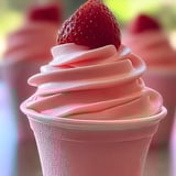 A pink frosted cupcake topped with a fresh strawberry.