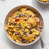 Beans and tomatoes tossed with crunchy nacho chips in a bowl.