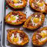 A tray holding baked potatoes stuffed with cheese, bacon, and eggs.