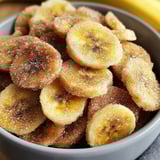 A bowl full of banana slices rolled in sugar.