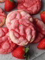 A plate of red sugar cookies with strawberries on top.
