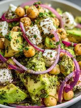 A close up of a salad with chickpeas, feta cheese, and avocado.