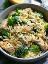 A bowl filled with chicken and broccoli orzo.