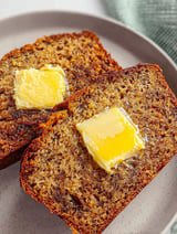 Two slices of banana bread with butter on top.