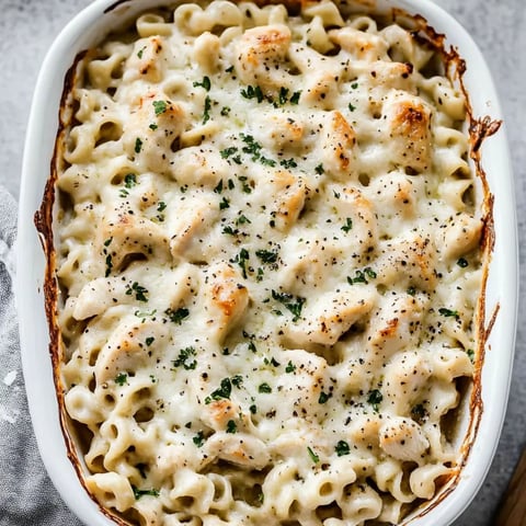 A warm bowl of creamy pasta with chicken pieces.