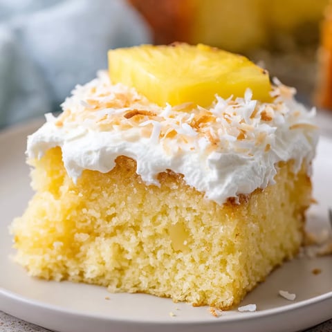 A piece of cake with fluffy white topping and a slice of pineapple up top.