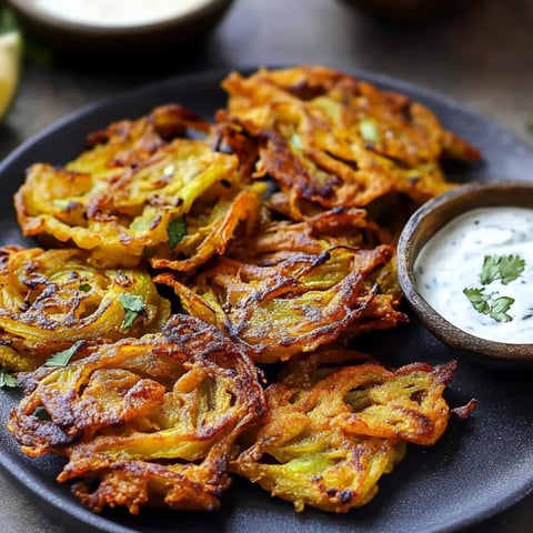 Crispy onion fritters with a bowl of dip on the side.