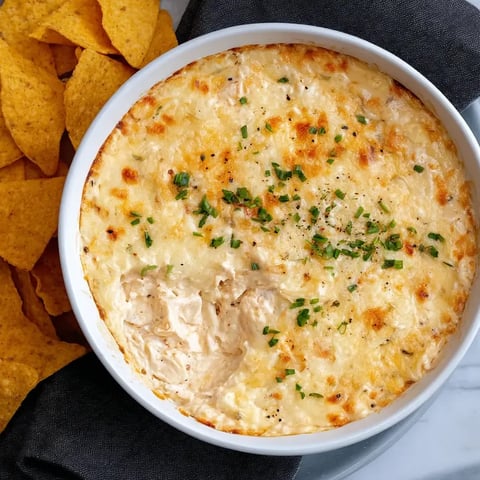 A bowl of cheese dip with chips.