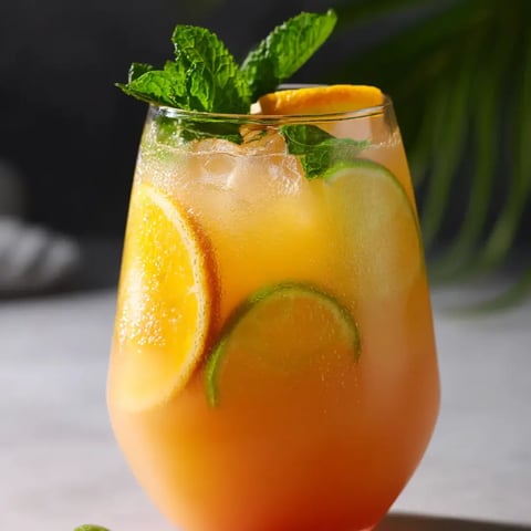 Orange juice served in a glass with lemon on the rim.