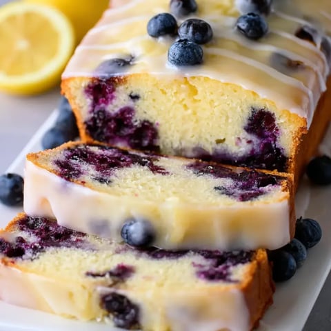 Bright loaf slice of blueberry and lemon, lemon slice sitting on the top.