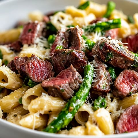 A big bowl packed with juicy steak, asparagus, and pasta.