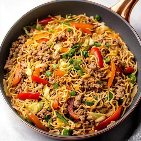A bowl full of noodles, veggies, and chicken sitting together.