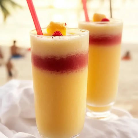Two chilled orange drinks in glasses with straws.