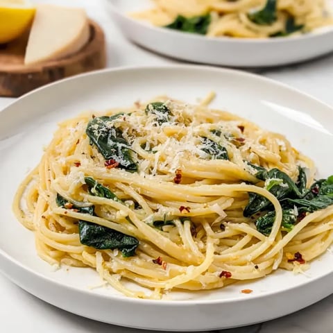 Spaghetti tossed with spinach and parmesan on a plate.
