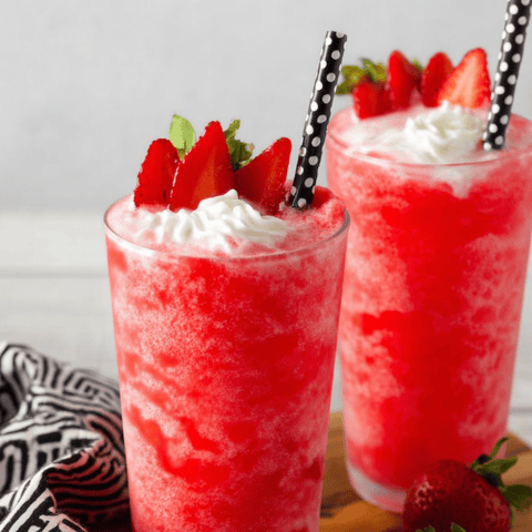Two big glasses holding pink strawberry drinks, loaded with ice.