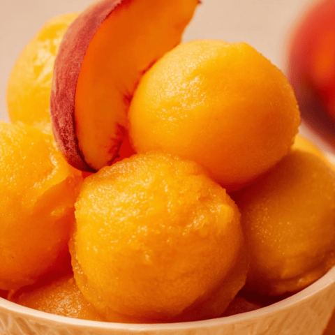 A dish filled with peaches and plums sitting together.