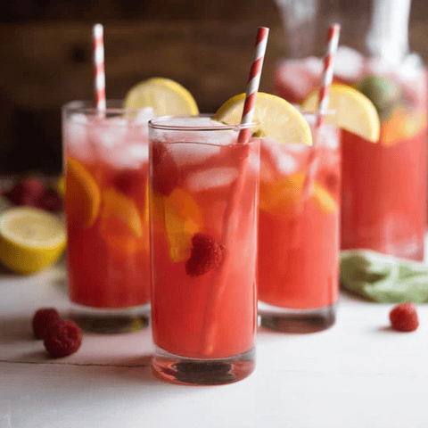 Three glasses filled with pink lemonade and straws inside.