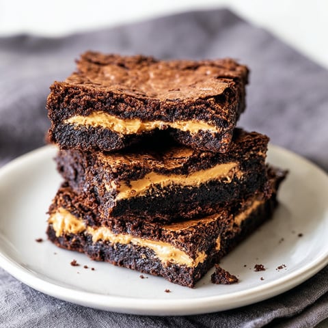 Chocolate squares packed with caramel and peanut butter sit on a plate.