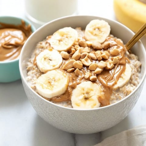 A bowl of oats topped with banana slices and a swirl of peanut butter.