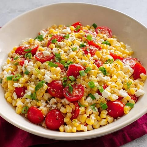 A bowl filled with corn and bright tomatoes.