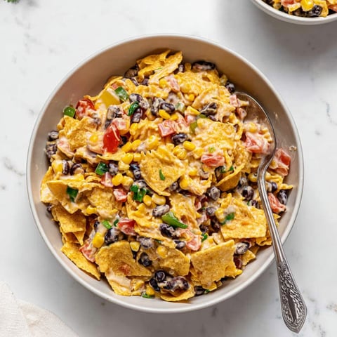 Beans and tomatoes tossed with crunchy nacho chips in a bowl.