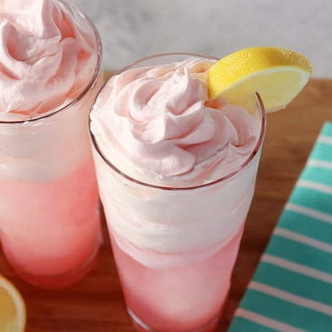 Two glasses of pink drink with lemon slices.