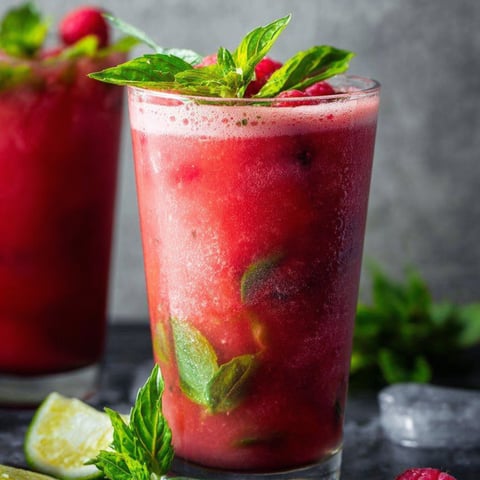 A glass filled with red punch and some mint on top.