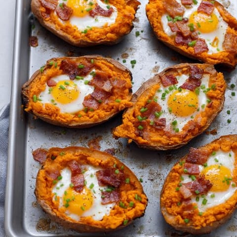A tray holding baked potatoes stuffed with cheese, bacon, and eggs.
