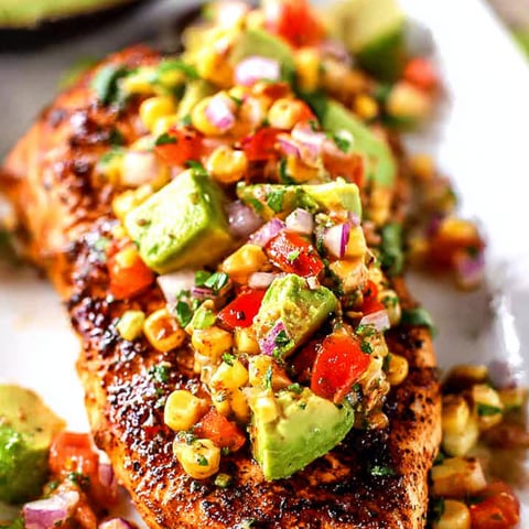Chicken with corn and avocado on a plate.