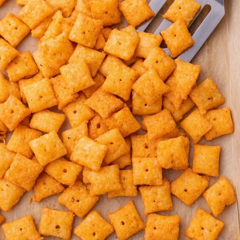 A pile of cheese crisps on a cutting board.