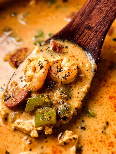 A wooden spoon in a bowl of Cajun White Chicken Chili.