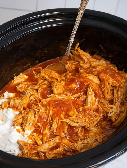 A close up of a crock pot with chicken in it.