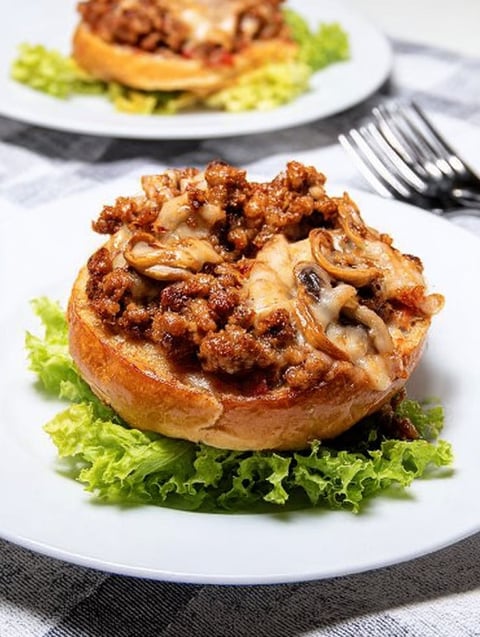 A plate of food with a burger and mushrooms on top.