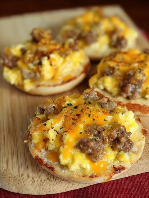 A breakfast pizza with cheese and sausage on top.