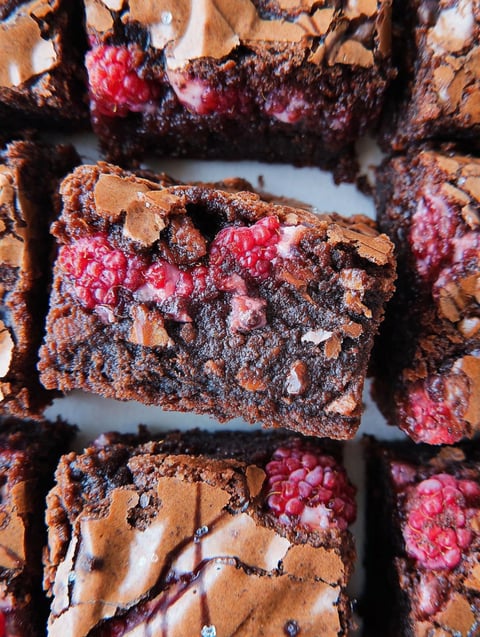 Close up shot of chocolate brownie topped with fresh raspberries.