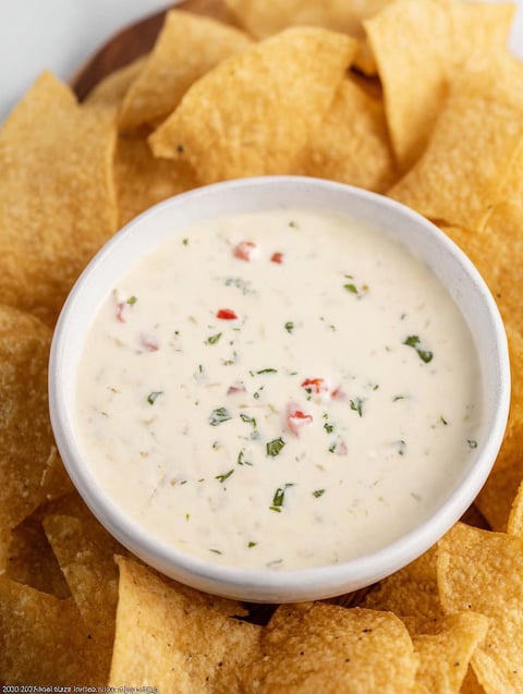 Bowl of white cheese dip with chips ready to eat.